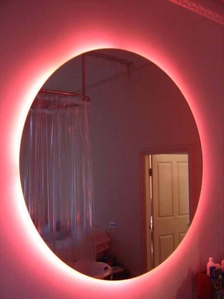 a bathroom mirror with a pink light around it