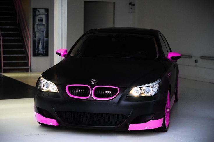 a black and pink car parked in a garage