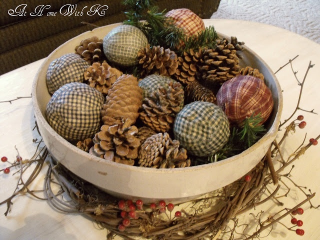 a bowl filled with lots of pine cones and other decorations on top of a table