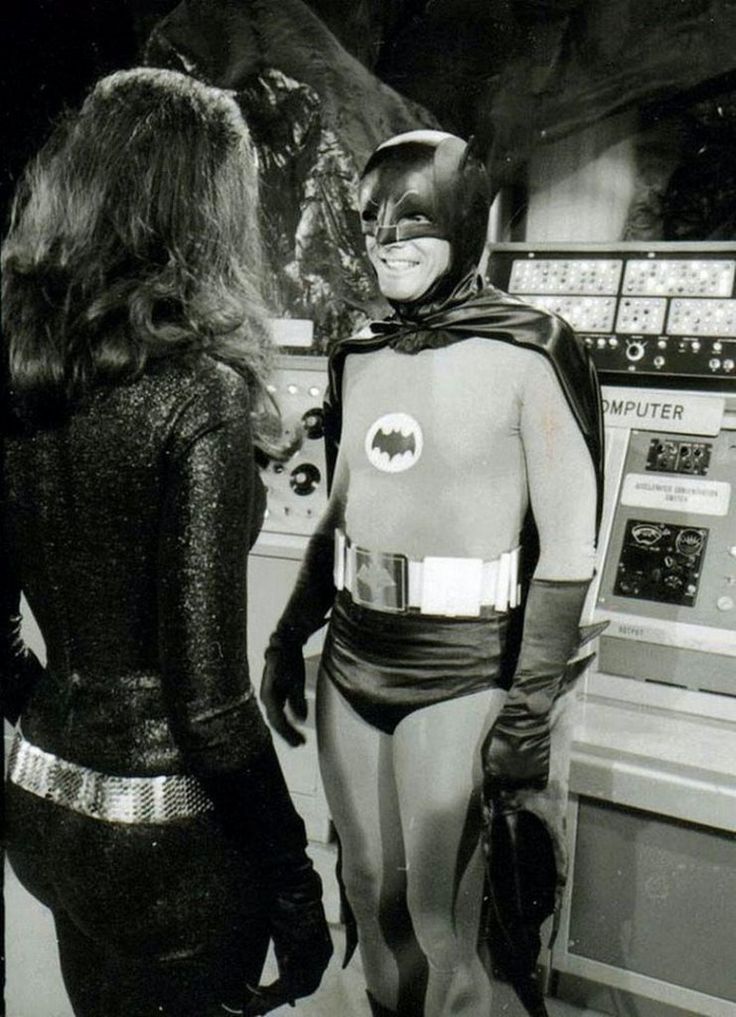 two women dressed as batman and one is talking to each other in front of an atm machine