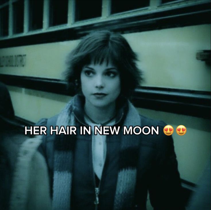 a woman standing in front of a bus with her hair in new moon