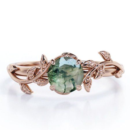 a ring with an oval green stone in the center and leaves on each side, surrounded by diamonds