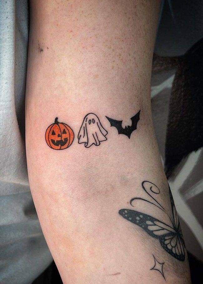 a person with a tattoo on their arm that has two pumpkins and a ghost