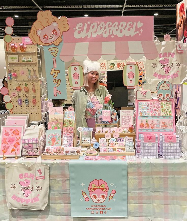 a woman standing in front of a table filled with cards and paper goods for sale