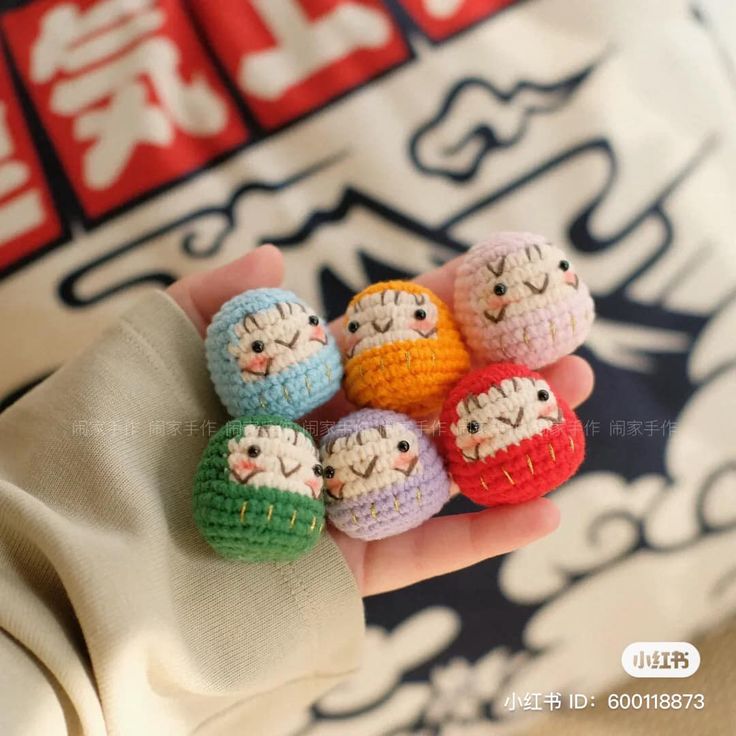 small crocheted dolls are held in someone's hand with chinese characters on it