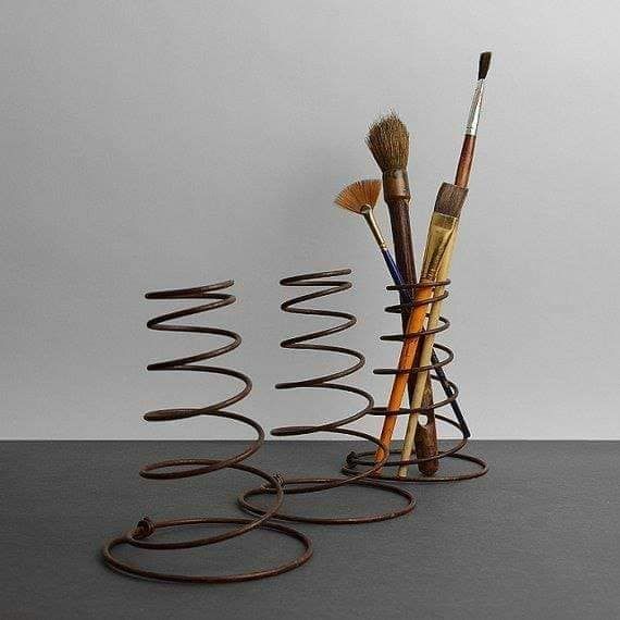 an assortment of brushes are arranged in a spiral design on a table with grey background