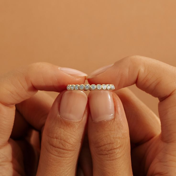 a woman's hand holding a diamond ring in front of her face and the other hand