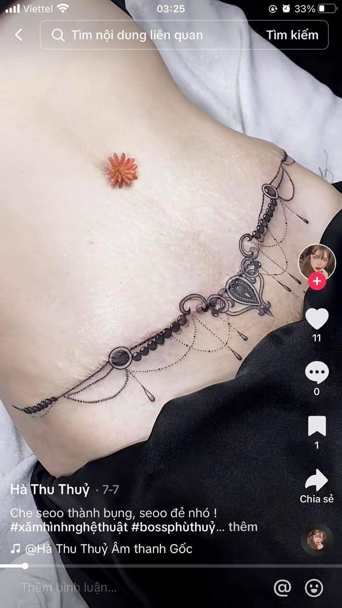 a woman's stomach with an orange flower attached to the chain on her belly