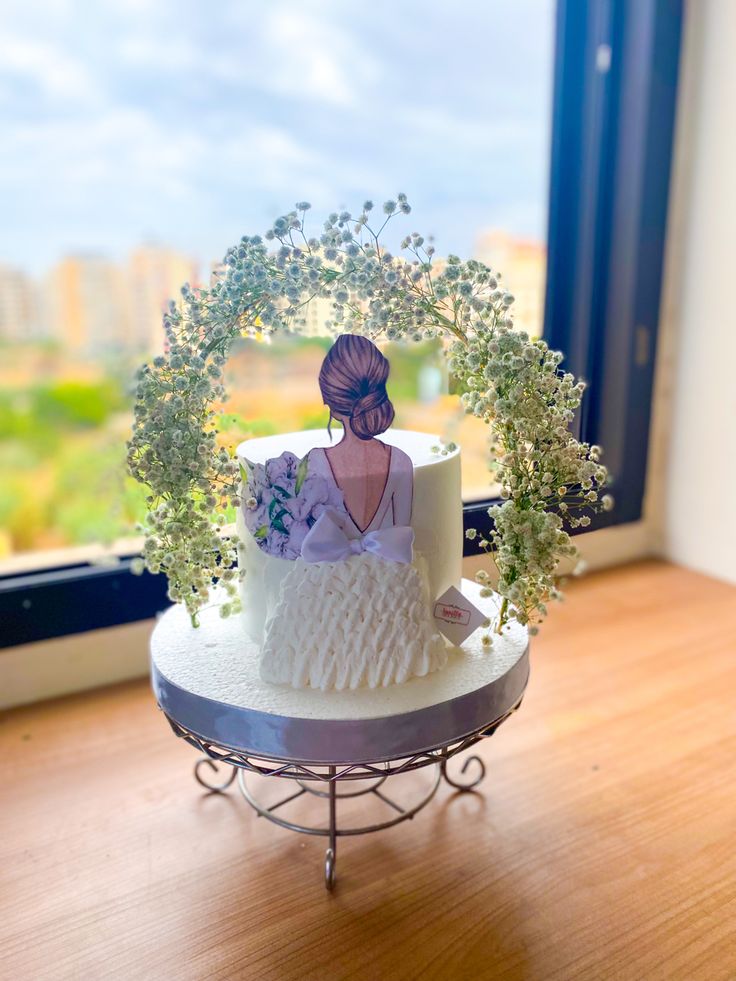 there is a wedding cake with flowers on the table next to the window sill