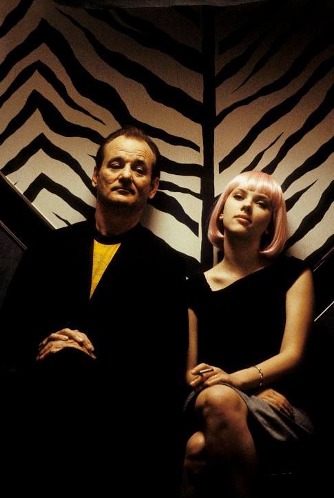 a man and woman sitting next to each other in front of a zebra print wall