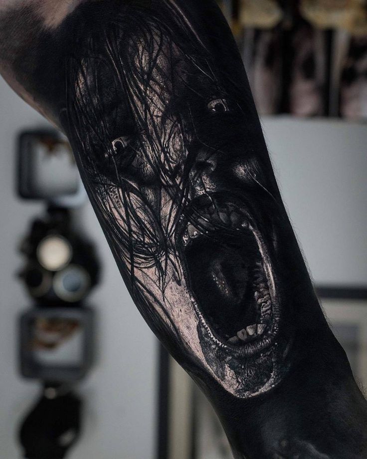 a man's arm is covered in black and white ink with an evil face