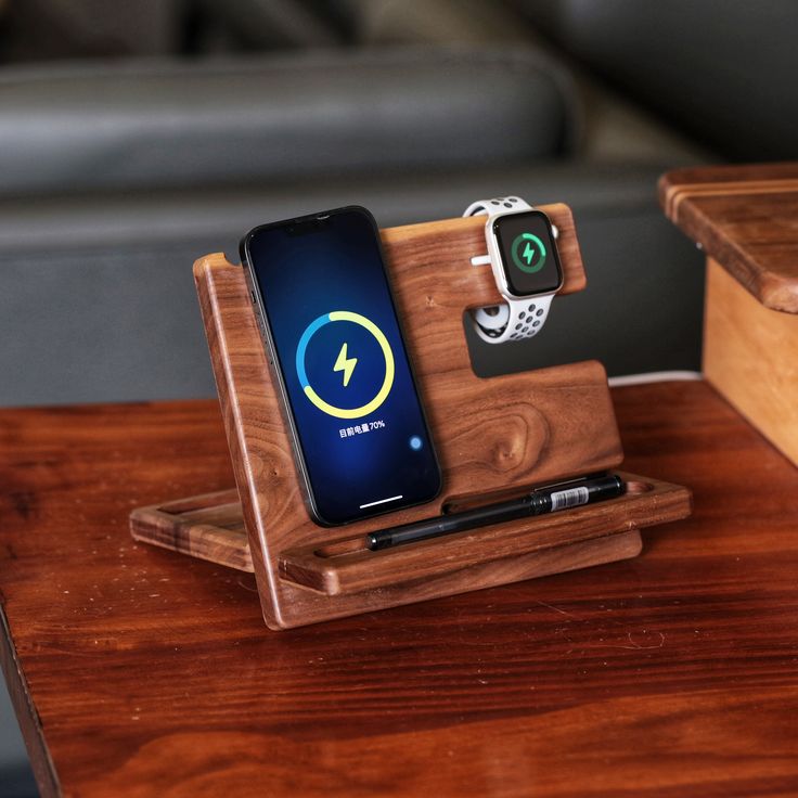 an apple watch charging station on a wooden table with a cell phone and charger