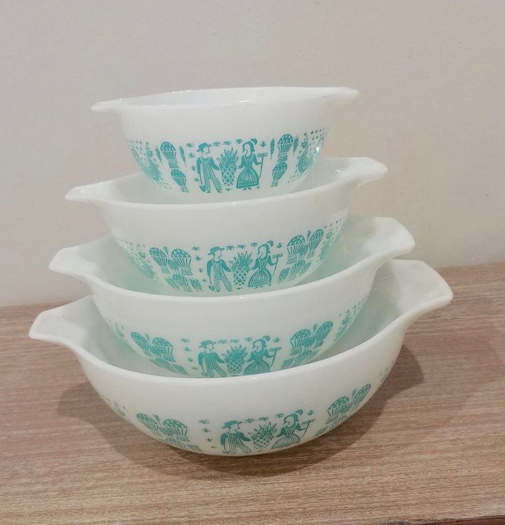 four bowls stacked on top of each other in blue and white designs, sitting on a wooden surface