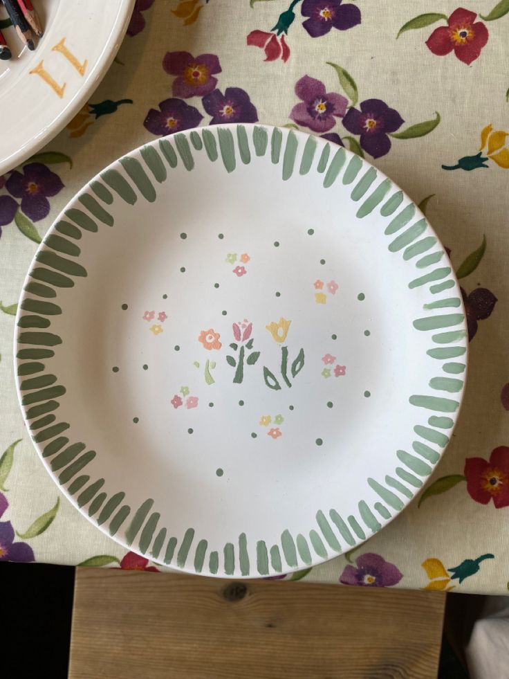 a plate with flowers painted on it sitting on a table next to a knife and fork