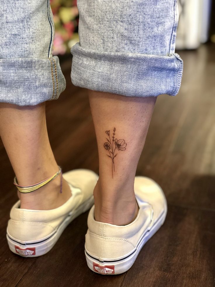 a woman's foot with a small flower tattoo on her left side calfocks