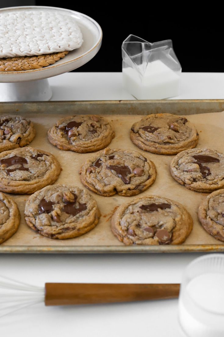 chocolate chip cookies and marshmallows on a baking sheet with a cookie tray in the background