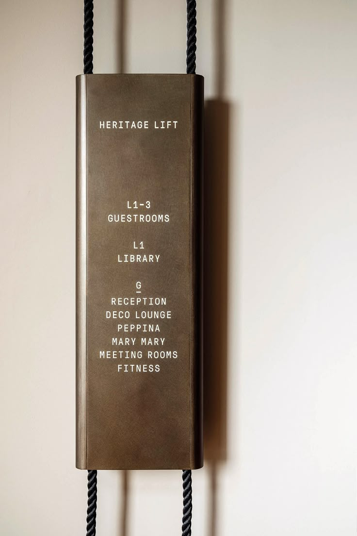 a book hanging on a wall with rope attached to it's sides and the words heritage list written in white