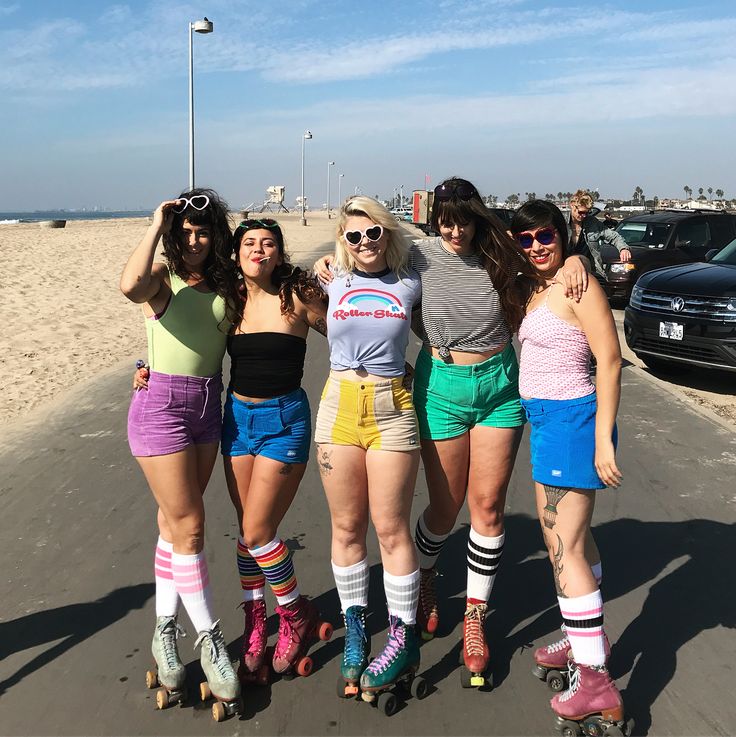 four girls are standing on roller skates at the beach