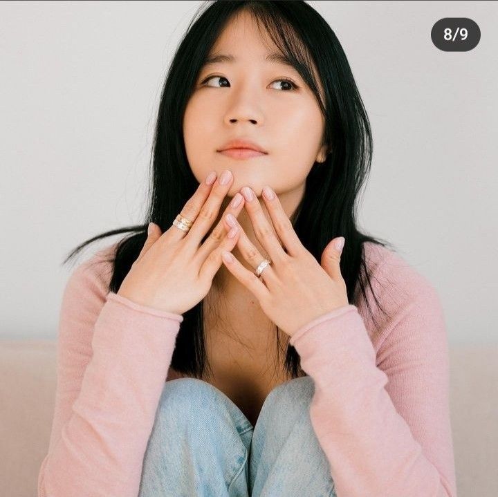 a woman sitting on top of a couch holding her hands in front of her face