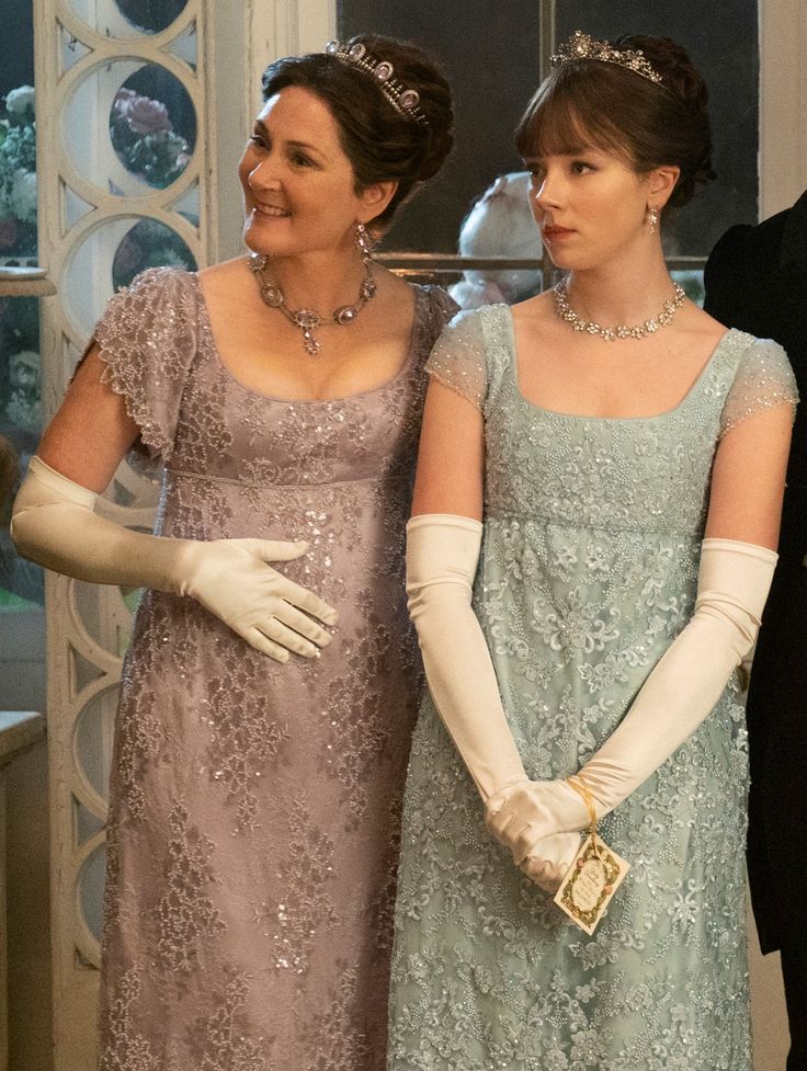 two women in evening dresses and gloves standing next to each other with their hands on their hips