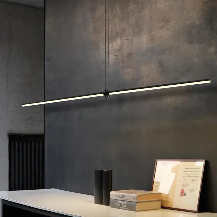 a table with some books on it next to a wall mounted light and a framed photograph