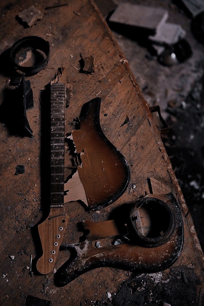 an electric guitar being worked on by a pair of pliers and wrenches in a workshop