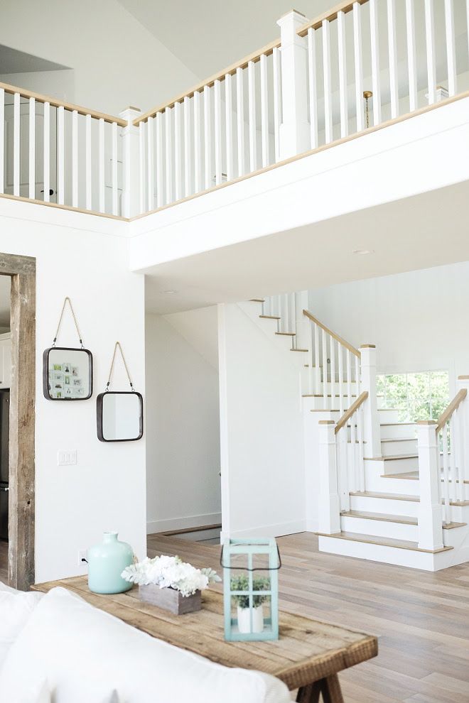 a white room with stairs and pictures hanging on the wall next to a coffee table