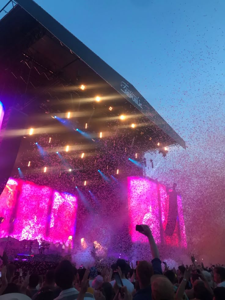 a large group of people at a concert with confetti thrown in the air