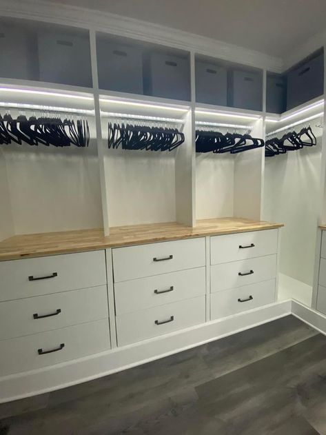 a walk in closet with white cabinets and drawers