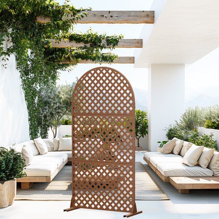 an outdoor living area with white couches and wooden pergolated screens on the wall