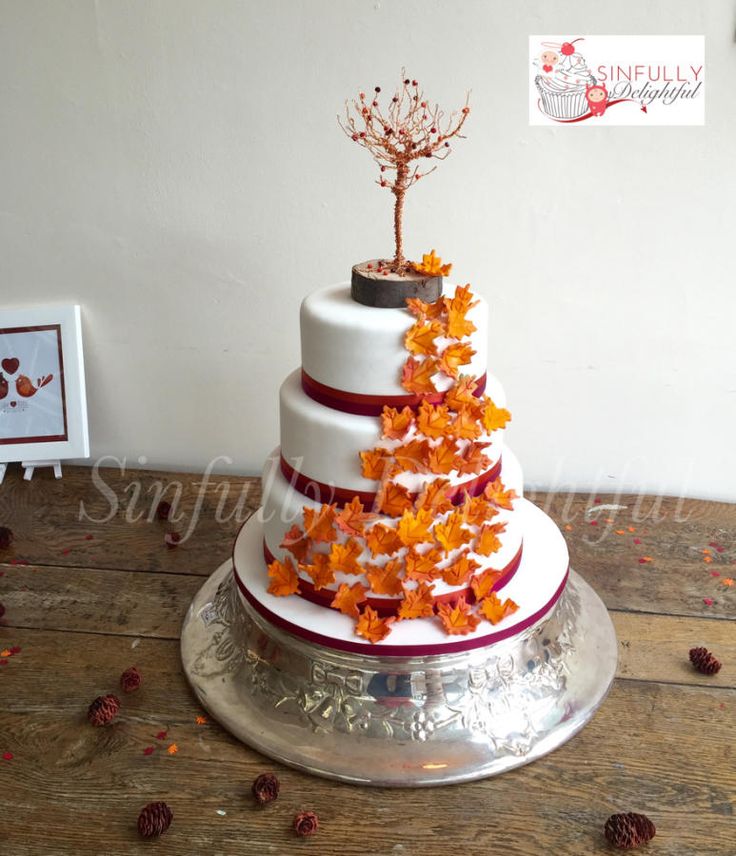 a three tiered cake decorated with orange leaves