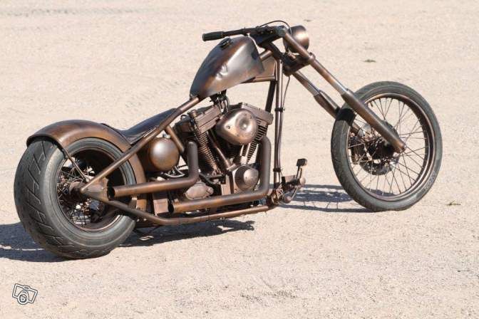 a motorcycle that is sitting in the sand with no wheels on it's side