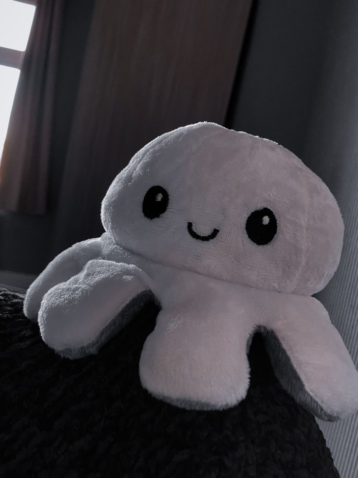 a white stuffed animal sitting on top of a bed