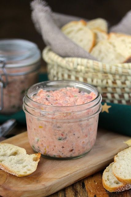 a jar filled with food sitting on top of a wooden cutting board next to bread