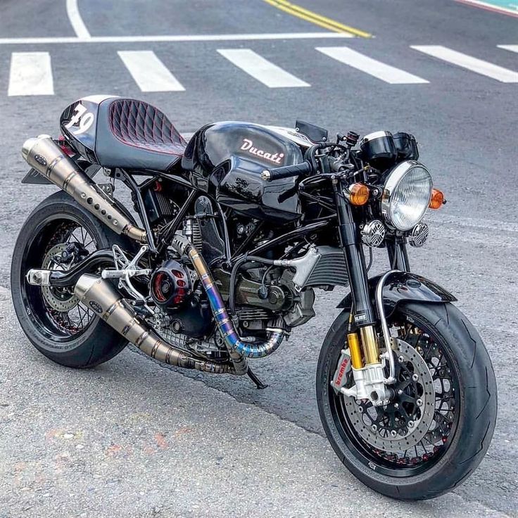 a black motorcycle parked on the street next to a parking lot with no one around it