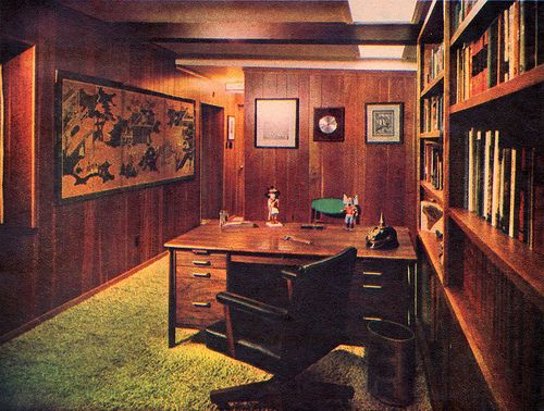 an office with wood paneled walls and green carpeting on the floor is shown