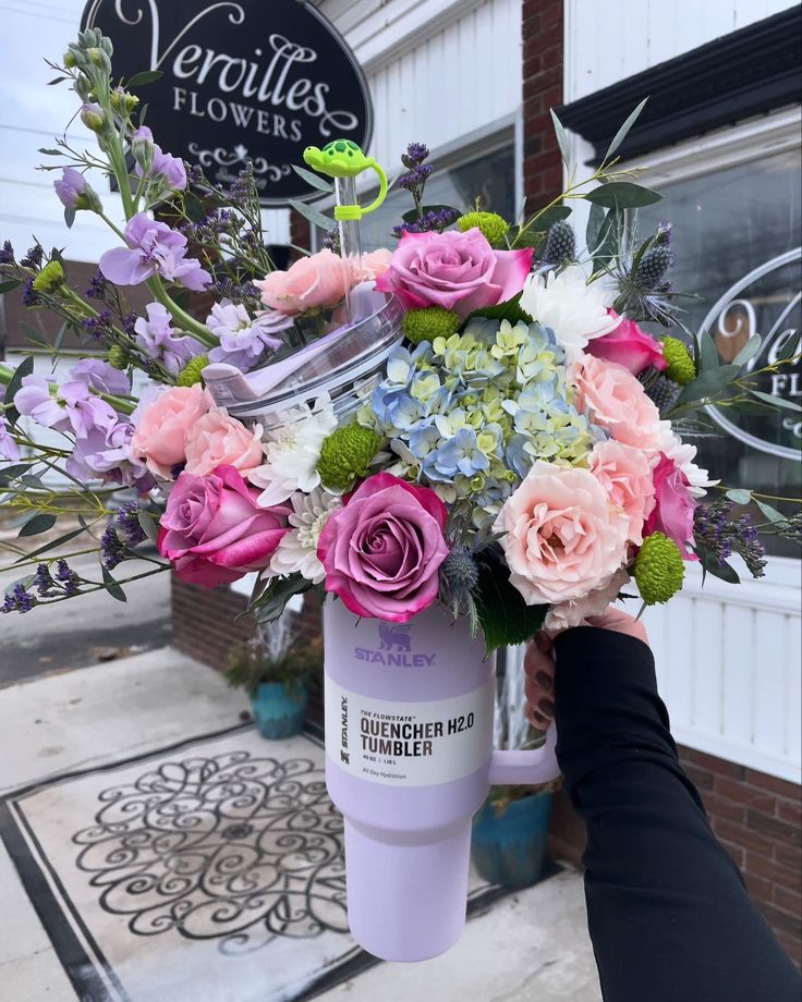 a bouquet of flowers is being held up in front of a flower shop