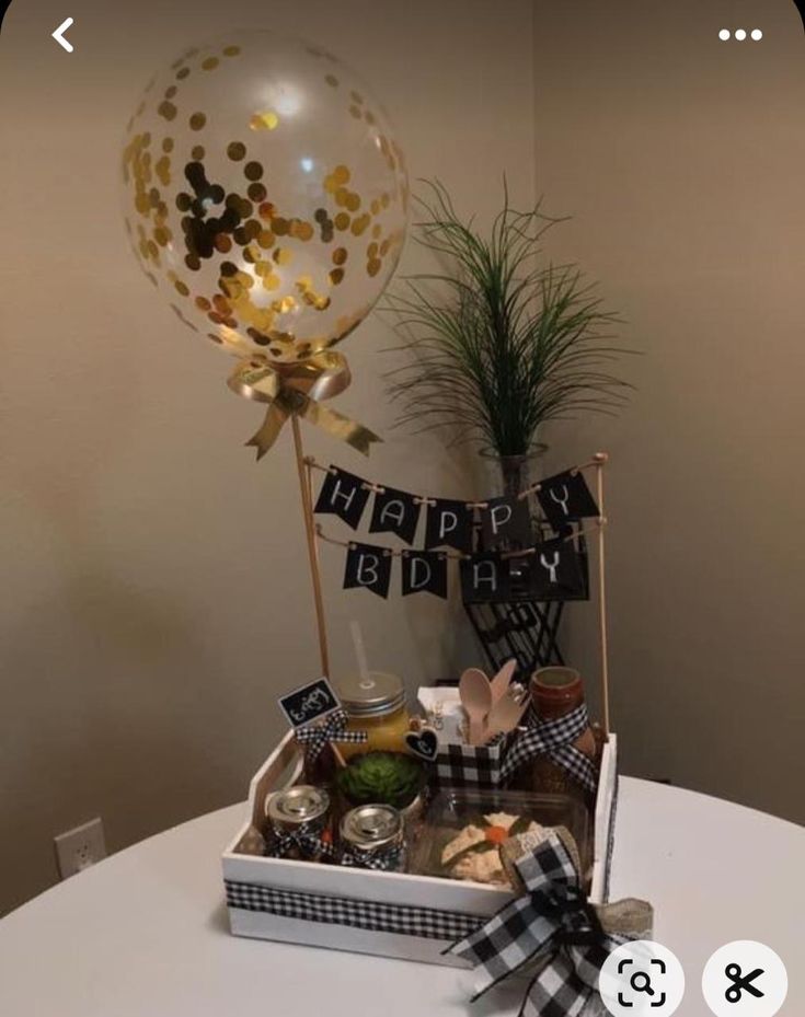 a birthday gift basket on a table in front of a balloon