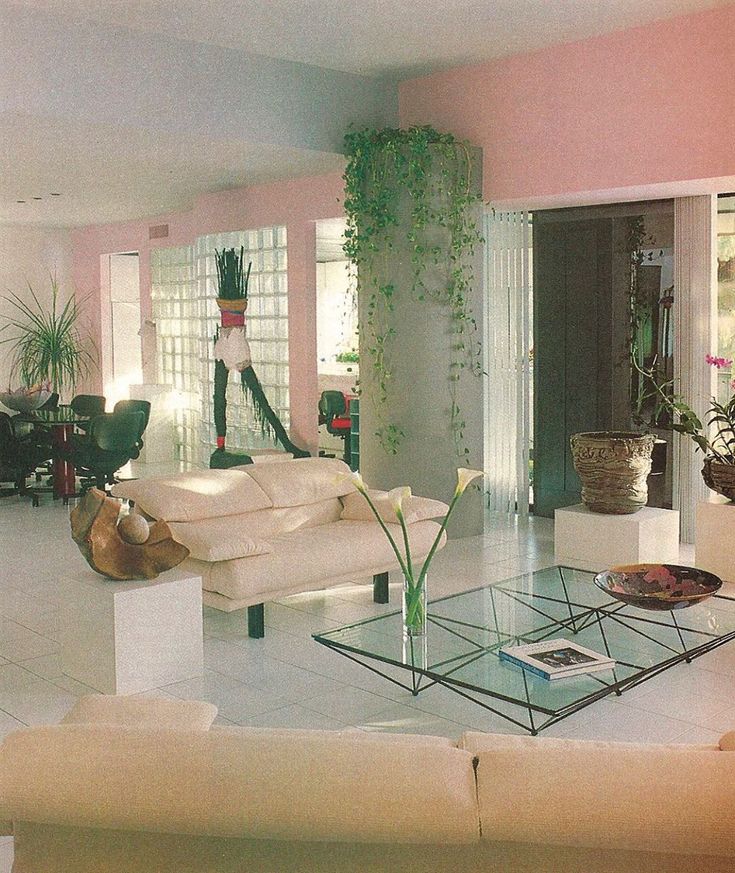 a living room filled with lots of furniture next to a tall white plant in the corner