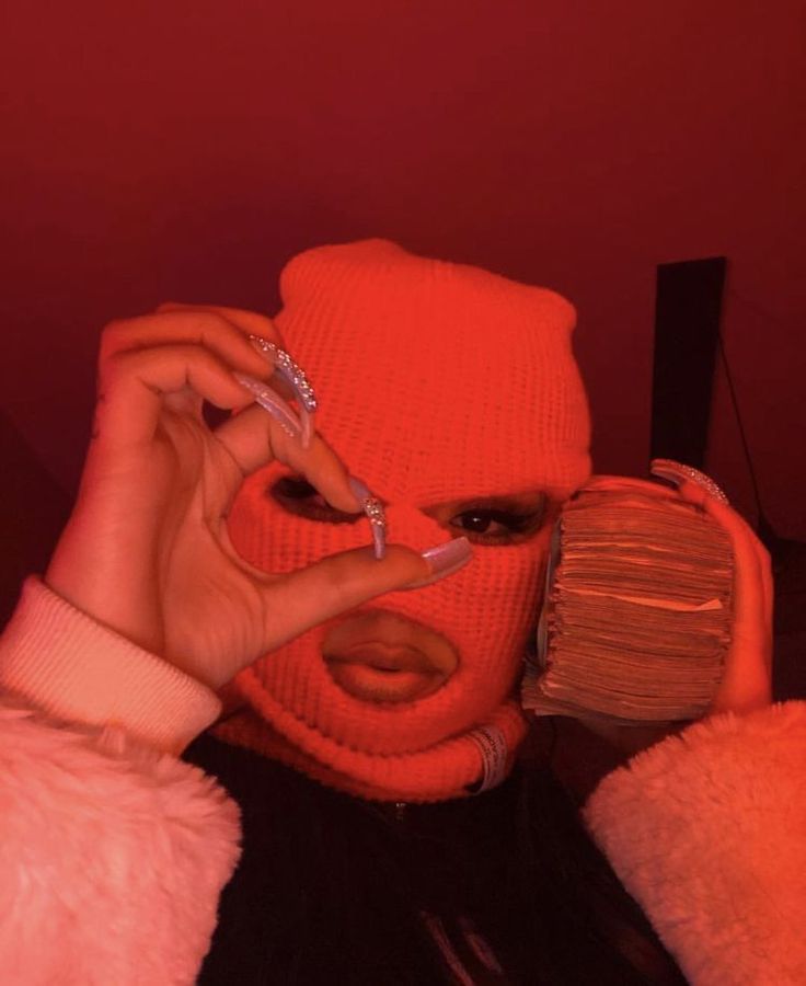 a woman wearing an orange knitted hat and holding a cell phone up to her face