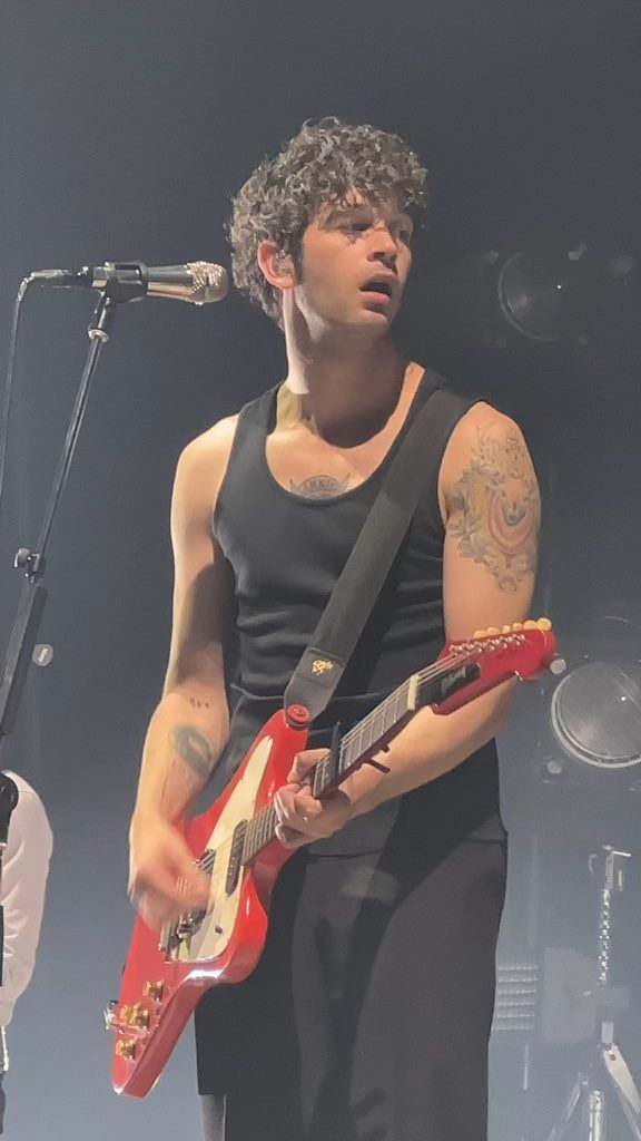 a man holding a guitar while standing in front of a microphone