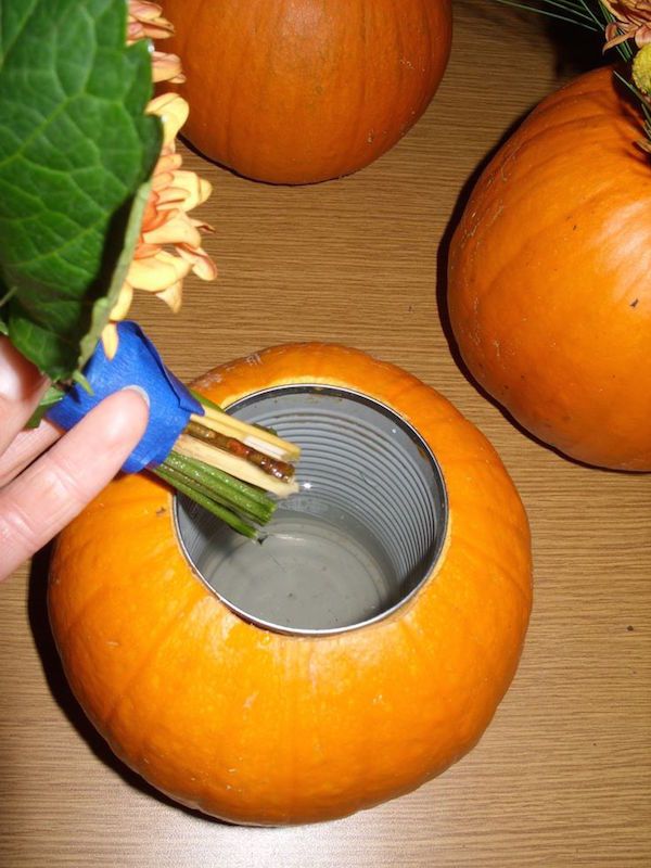 a person holding a bunch of oranges in front of some pumpkins on a table