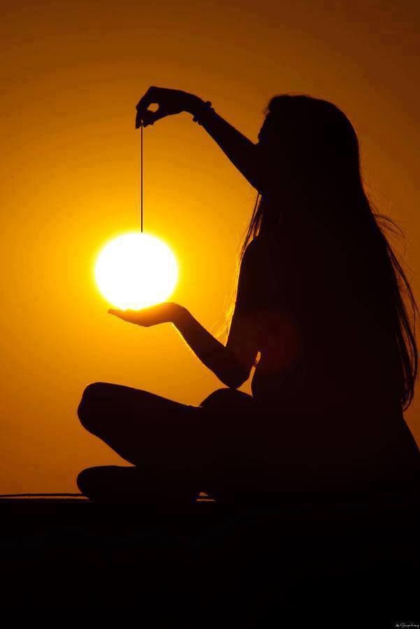 a woman is holding the sun in her hand