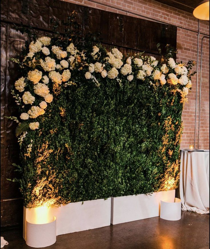 an artificial wall with flowers and candles on the floor in front of it at a wedding reception