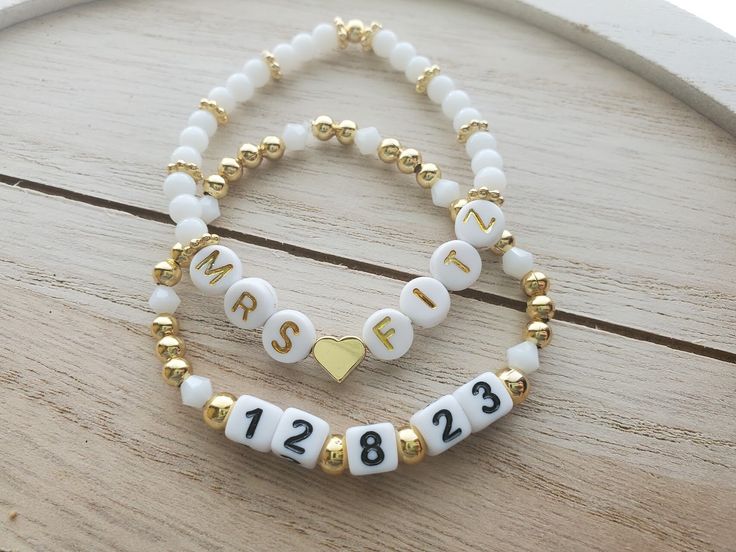 "This adorable bracelet set is perfect for a bride to be! The price is for both bracelets, but they can also be purchased separately if you only want one.  One bracelet says \"Mrs.\" and the bride's new last name. This bracelet is made with a gold 18k gold plated heart bead separating the Mrs. and the last name, white glass 4mm round beads, and 24k gold plated bumpy rondelle accent beads. It also has a gold plated round bead to cover the knot. The letters used are round white acrylic with gold l Bride Clay Bead Bracelet, Bracelet Team Bride, Gold Name Bracelet For Wedding, Customizable Bracelets For Weddings And Mother's Day, Adjustable White Bracelet For Anniversary, White Letter Beads Name Bracelet For Wedding, Gold Bracelets With Letter Beads For Wedding, Letter Beads Bracelet For Wedding, Elegant Letter Beads Jewelry For Wedding