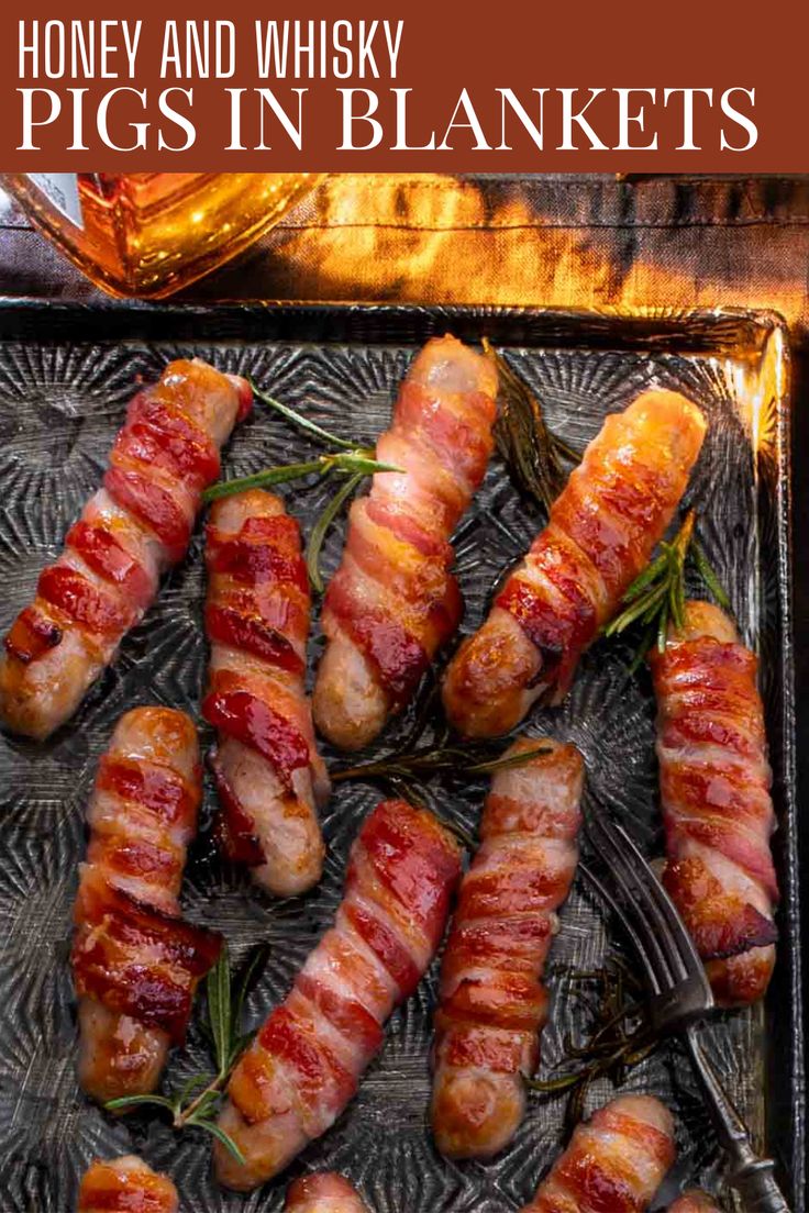 Cooked Pigs in blankets on a baking tray next to a bottle of whiskey. Pork Chipolatas, Pigs In Blankets, British Christmas, Cocktail Sausages, Christmas Sides, Pigs In A Blanket, Honey Glaze, Holiday Feast, Sunday Roast