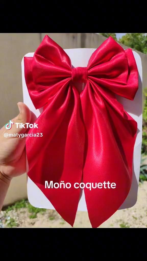 a hand holding up a red bow on top of a white card that says molo coquette