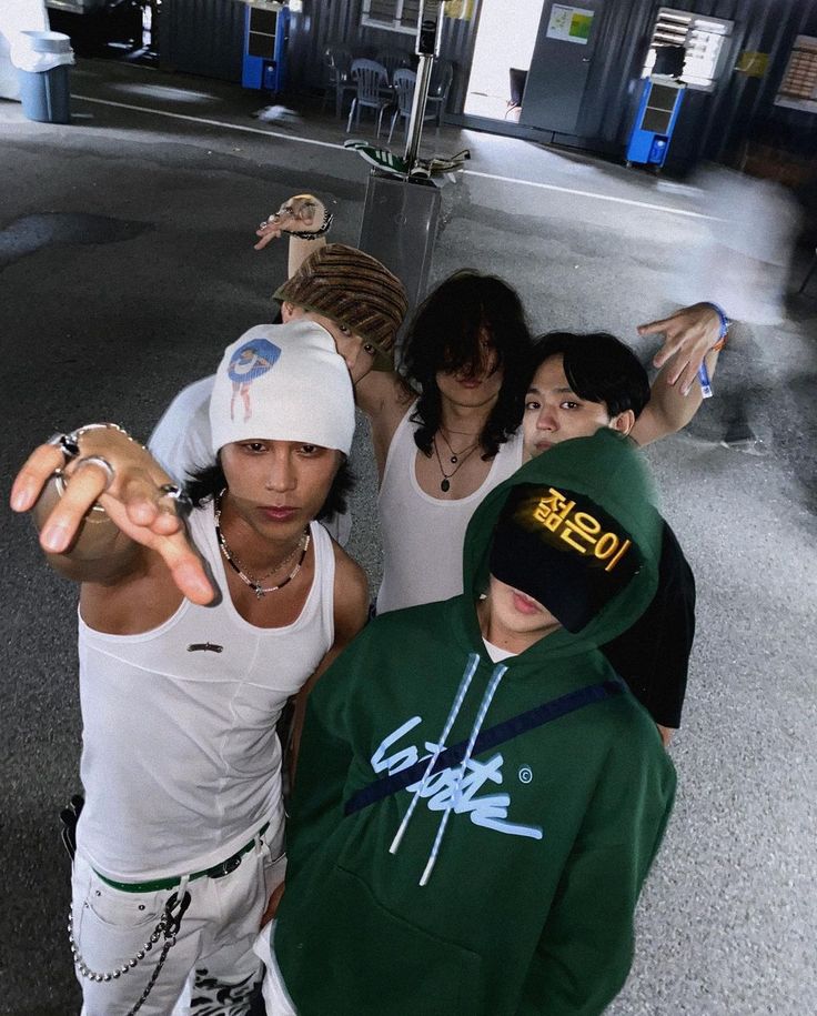 group of young people posing for the camera in front of an airport terminal with one pointing at the camera