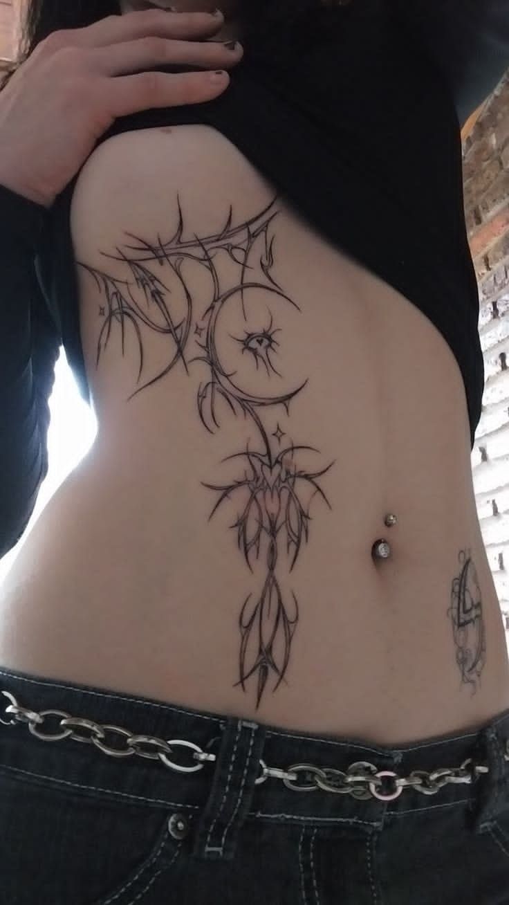 a woman's stomach with tattoos on it and some chains around her waist area