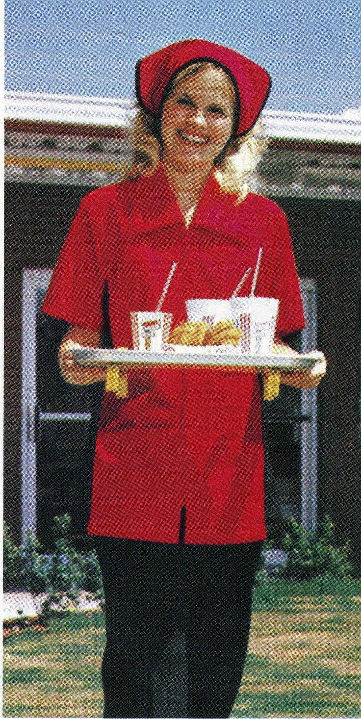 a woman in a red uniform holding a tray of food